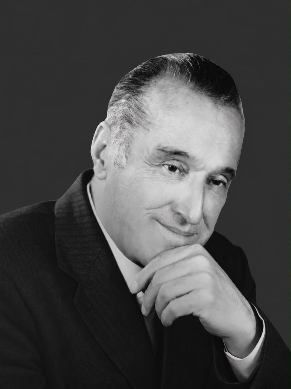 Black-and-white studio portrait of Ziyodullo Shahidi in a dark suit, his chin resting on his hand.